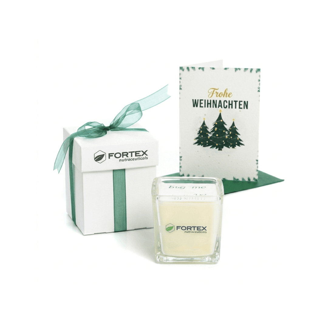 Weiße Fortex Geschenkbox mit grüner Schleife, Kerze im Glas und Weihnachtskarte mit Aufschrift Frohe Weihnachten.