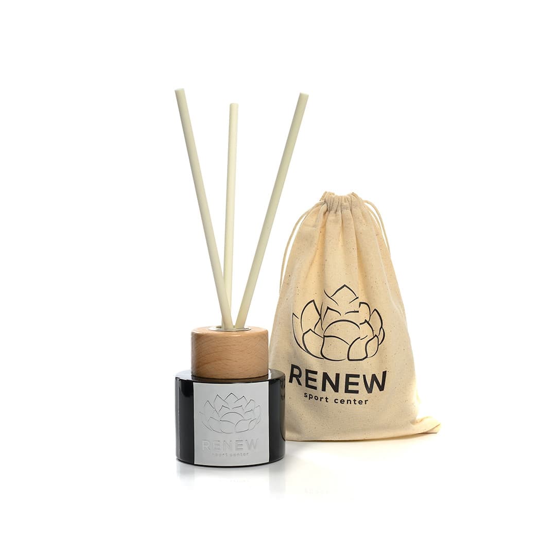 Schwarzer Raumduft-Diffusor mit Holzdeckel und drei Stäbchen neben einem cremefarbenen Stoffbeutel mit RENEW-Logo.